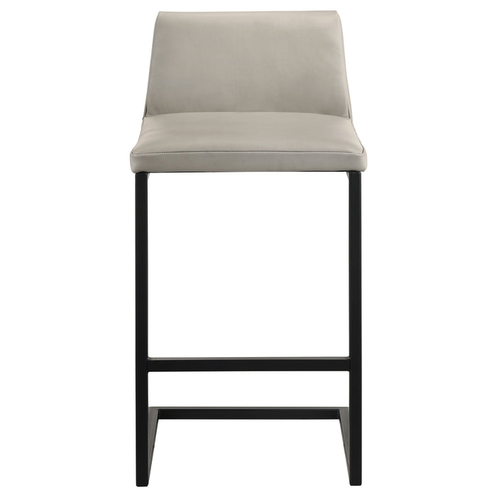 Pair of CoasterEveryday Vardon genuine leather bar stools in tan with metal legs, shown from a side angle.