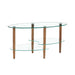 Modern Giga transparent oval glass coffee table with oak wood legs and three-layer design in a contemporary living room setting.
