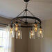 HomeRoots black metal chandelier with six transparent glass shades, modern lighting fixture for dining or living spaces.