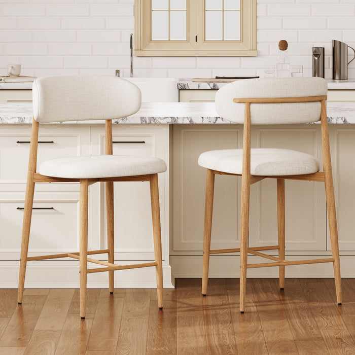 Set of two beige upholstered Giga counter height bar stools with wooden legs, suitable for kitchen islands.
