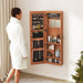 Giga jewelry armoire organizer with full length mirror, wall-mounted lockable cabinet and built-in LED light for jewelry storage.