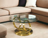 HomeRoots 32-inch round glass and gold metal coffee table with an abstract design, clear glass top and modern style.