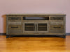 Distressed brown wood TV stand with enclosed storage, ideal for living room organization and entertainment setup.