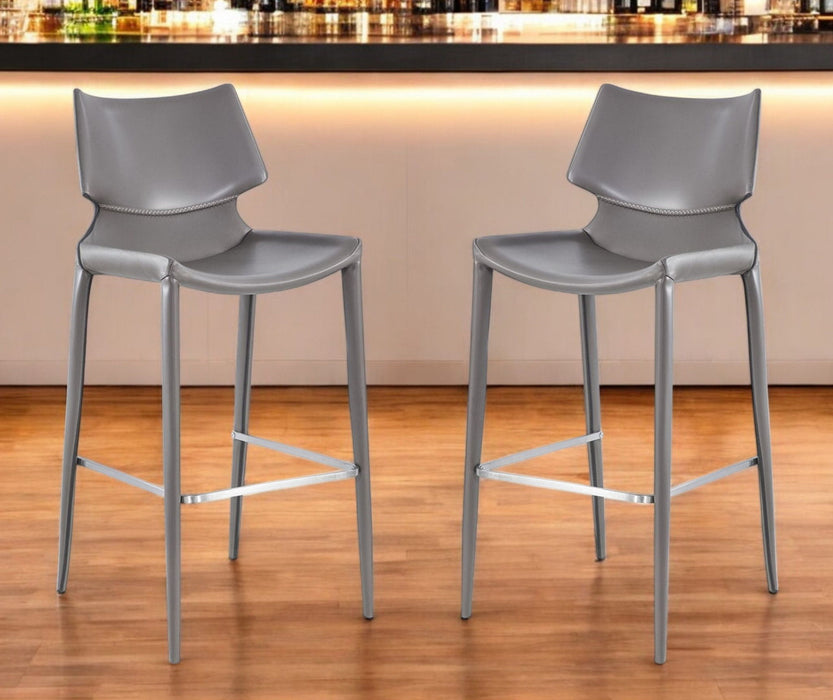 Set of two gray faux leather and steel low back bar height chairs with sleek design for modern bar or kitchen seating.