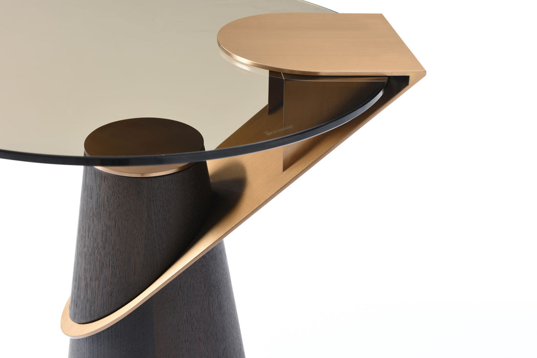 Round wooden and glass pedestal end table by HomeRoots with rose gold accents and clear glass top.