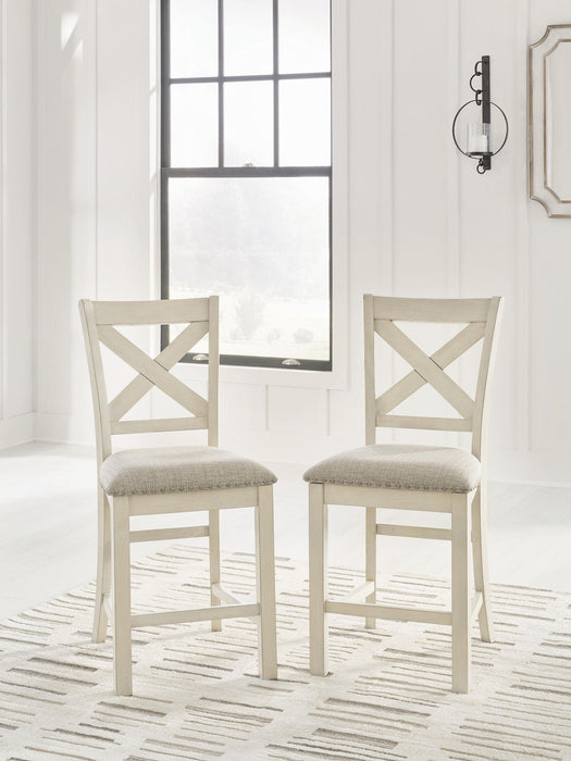 Set of two Robbinsdale upholstered barstools by Signature Design Ashley in antique white fabric with wooden legs.