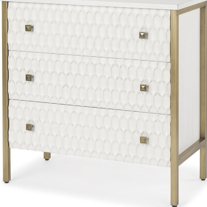 Wood and metal accent cabinet with gold and white finish, featuring carved geometric designs and three drawers for stylish storage.